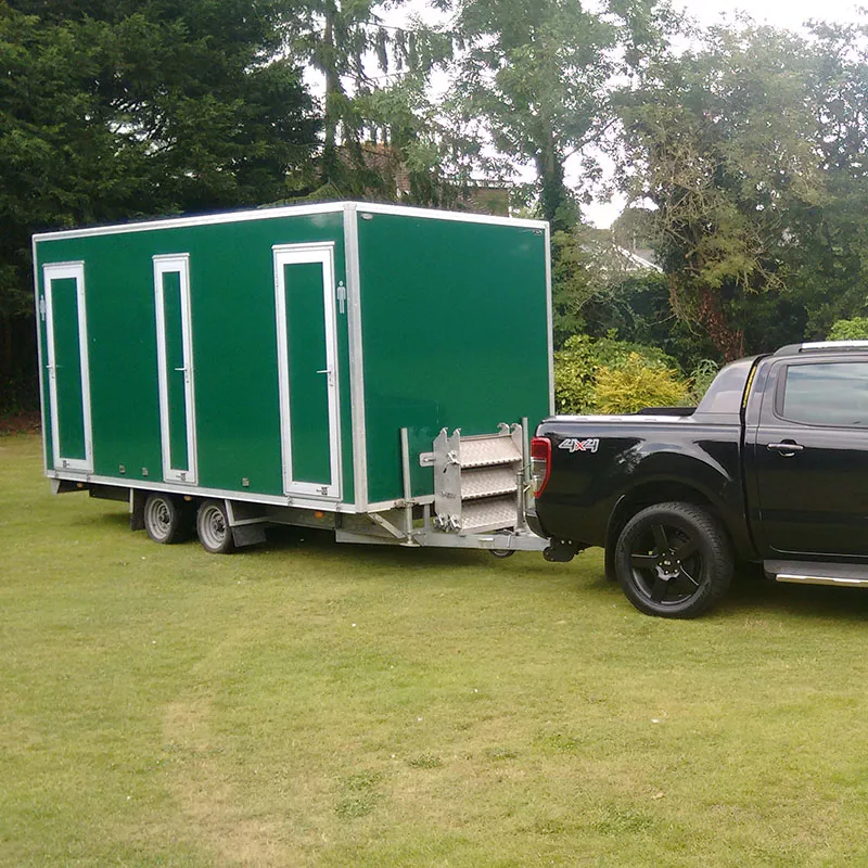 Our black 4x4 towing a green luxury toilet trailer across a lawn to an event